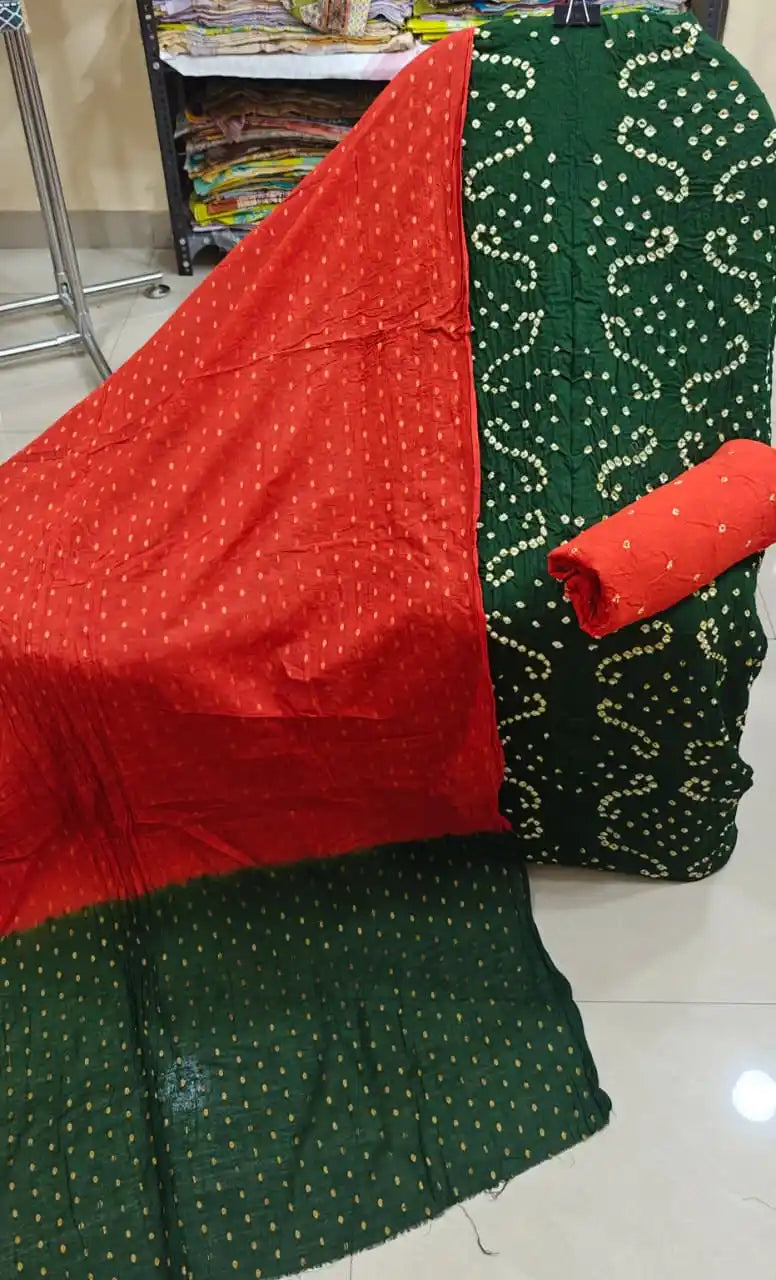 Deep bottle green cotton bandhani suit material showcasing elegant wavy tie-dye designs, styled with a bright contrast red dupatta.