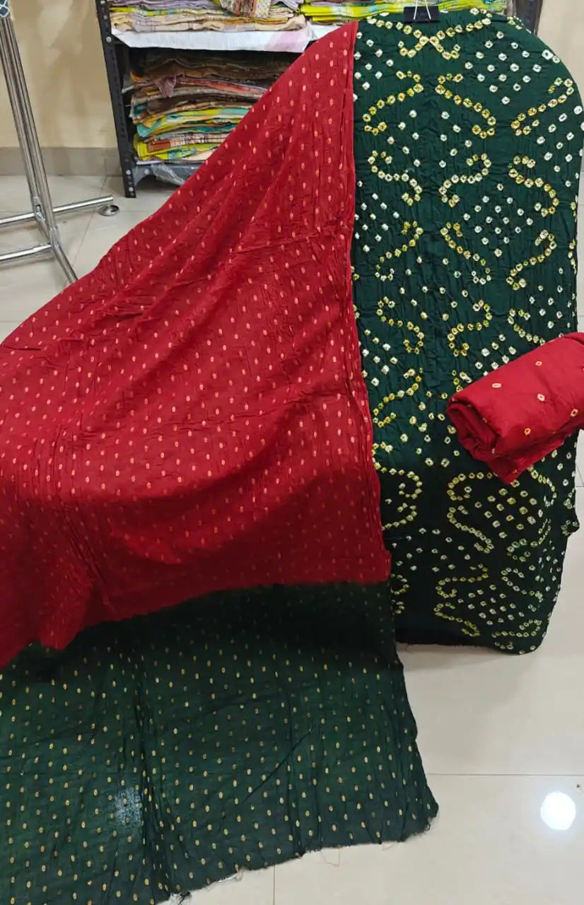 Dark forest green cotton bandhani dress material featuring intricate white tie-dye work, combined with a striking red contrast dupatta with golden highlights.