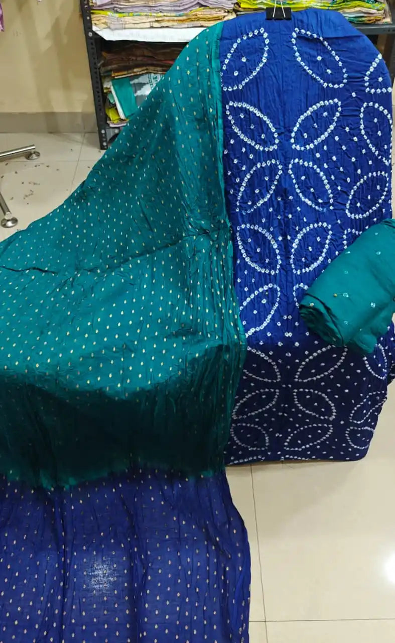 Royal blue cotton bandhani dress material with distinctive circular tie-dye patterns, styled with a deep teal-green contrast dupatta.