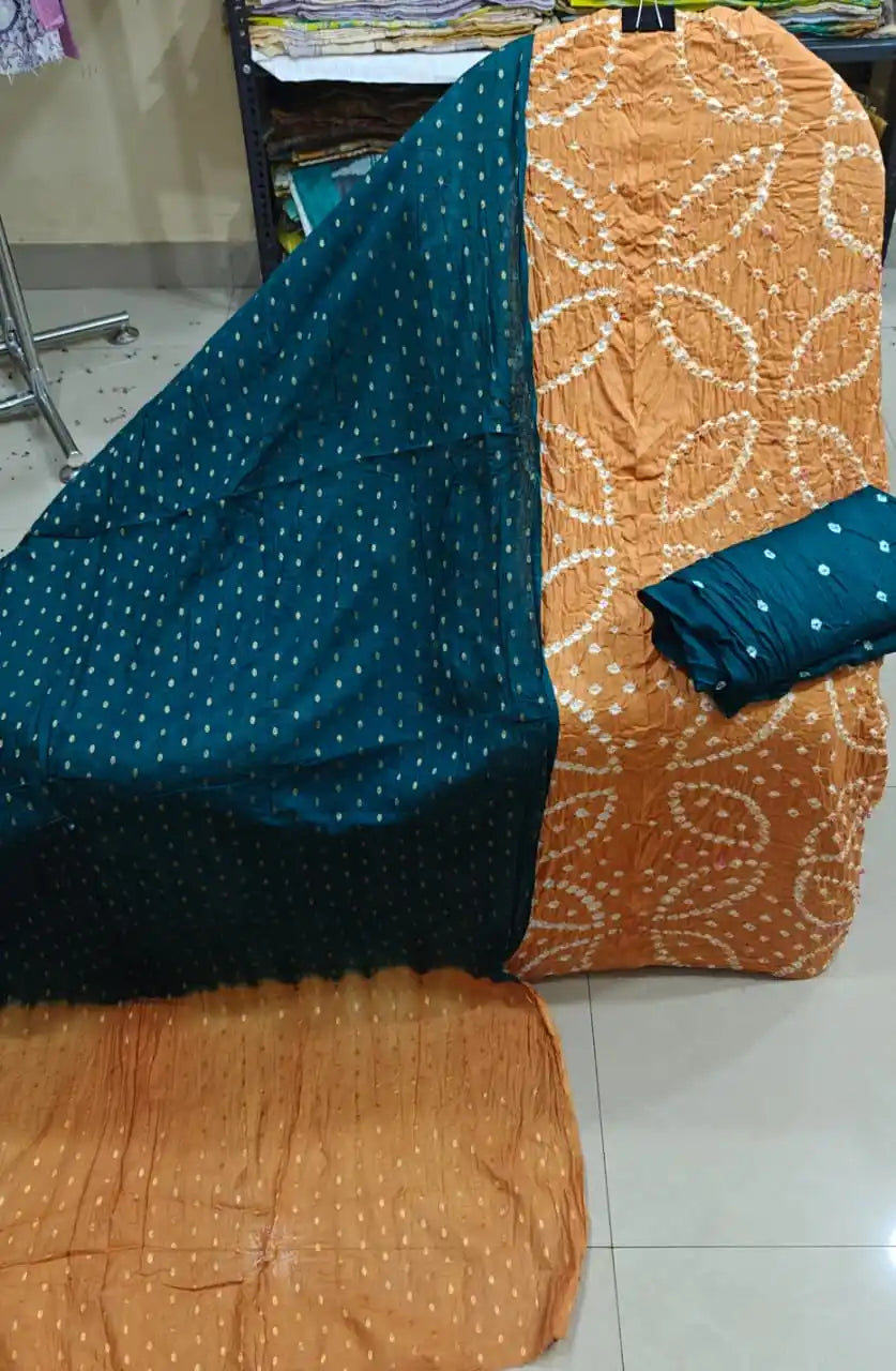 Light mustard orange unstitched bandhani suit material with floral-inspired tie-dye motifs, combined with a dark teal contrast dupatta.