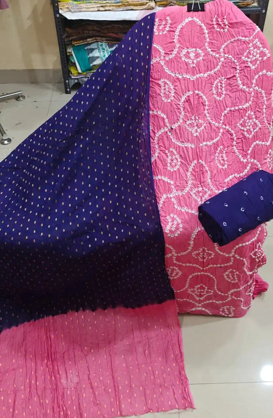 Bright pink unstitched bandhani dress material with white patterns, paired with a deep navy blue dupatta featuring golden foil print bootis.