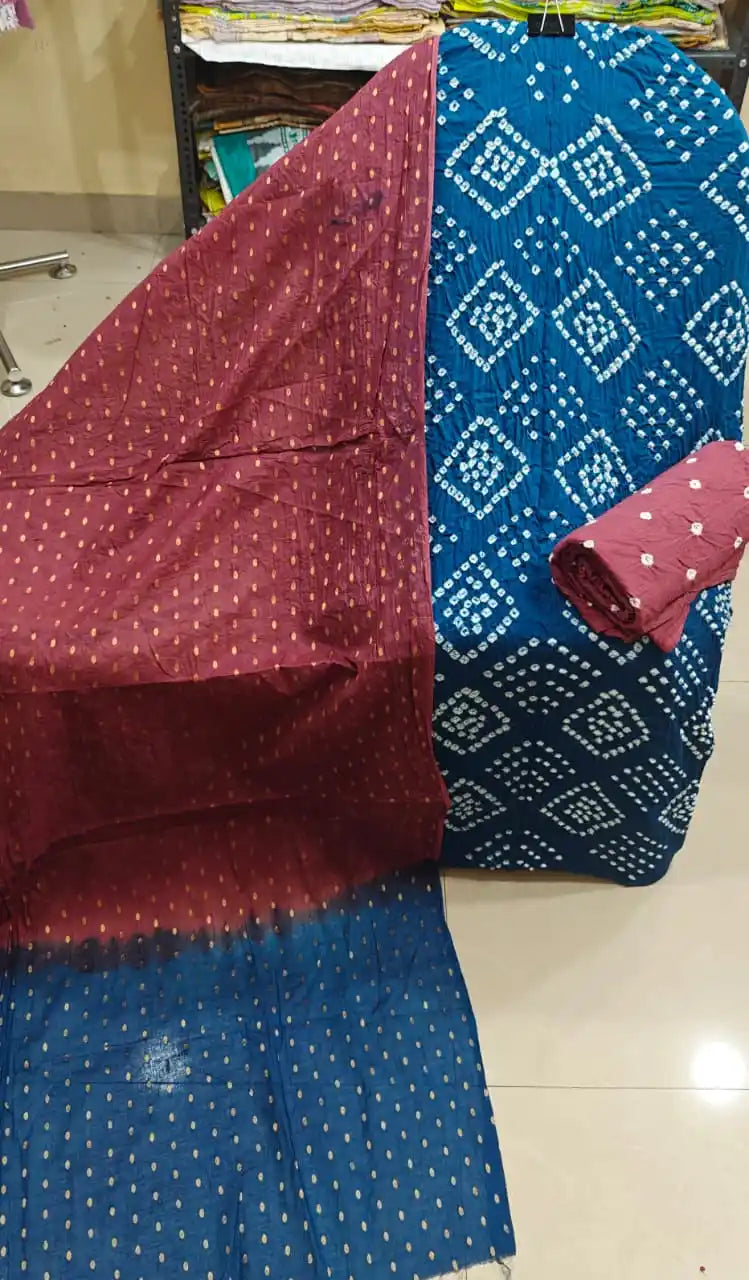 Vibrant teal blue unstitched cotton bandhani dress material with white diamond tie-dye patterns, paired with a contrast maroon dupatta featuring golden foil dots.