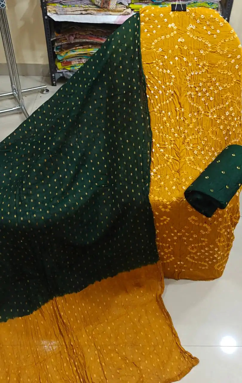 Bright mustard yellow cotton bandhani unstitched suit material with small white tie-dye prints, displayed with a deep emerald green contrast dupatta.