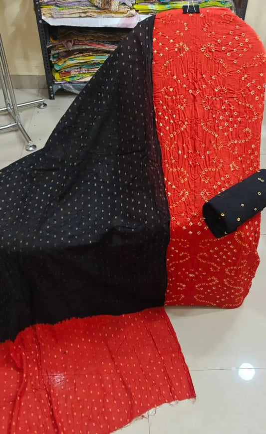 Striking scarlet red cotton bandhani dress material showcasing heavy yellow-white tie-dye work, paired with a classic midnight black contrast dupatta.
