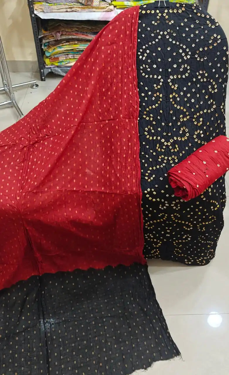 Jet black unstitched cotton bandhani dress material with white and yellow tie-dye patterns, paired with a vibrant red dupatta featuring golden foil dots.