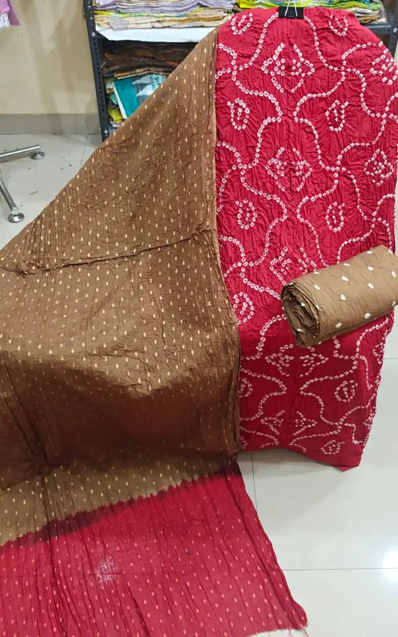 Deep red cotton bandhani unstitched suit material featuring white circular patterns, combined with a sober brown dupatta with gold zari highlights.