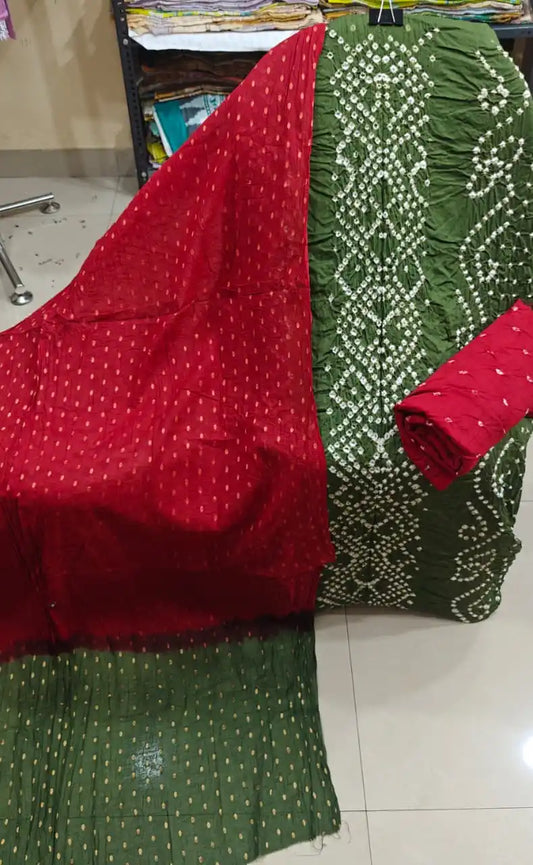 Deep olive green unstitched bandhani suit fabric with crisp white tie-dye designs, beautifully complemented by a bright red contrast dupatta.