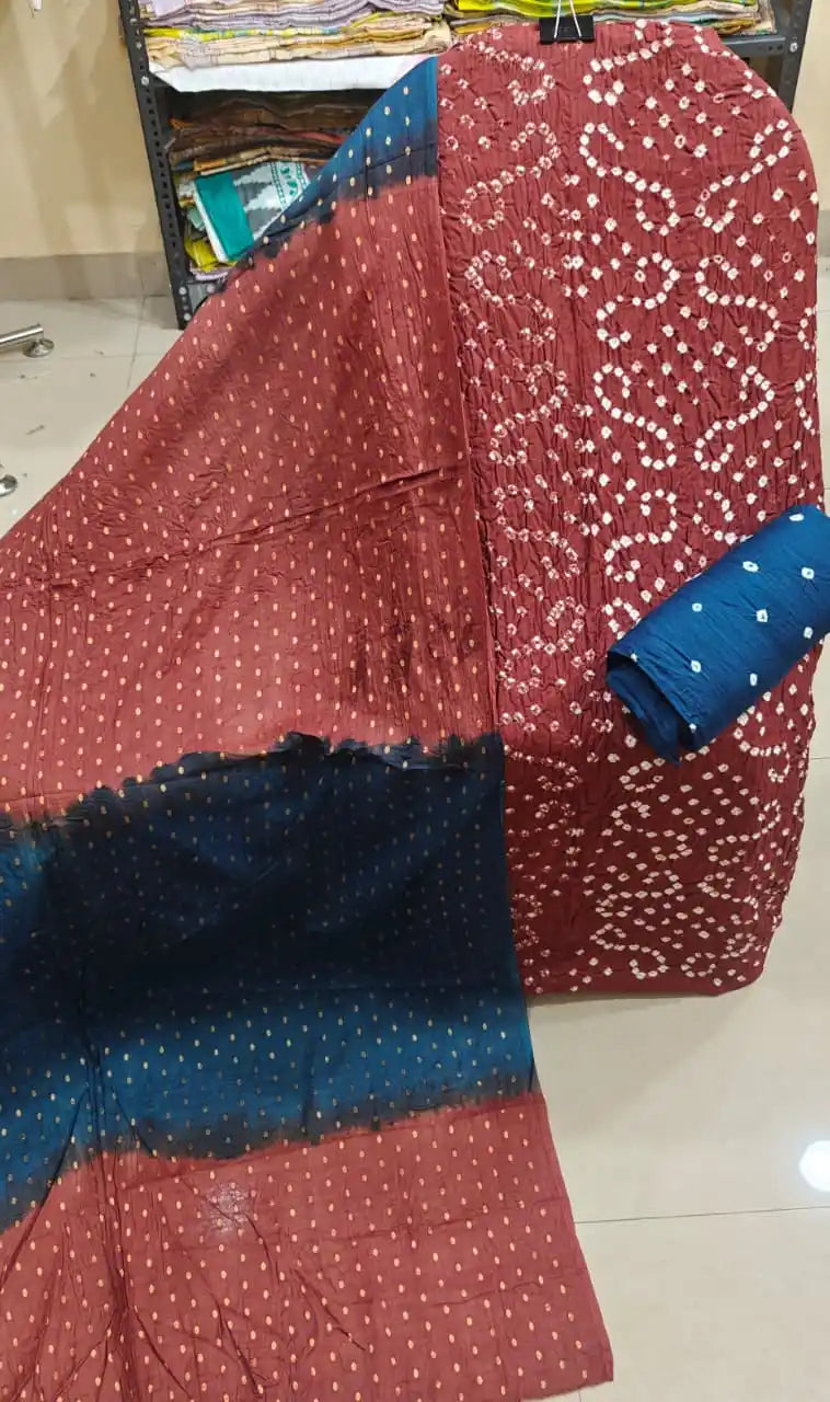 Traditional deep maroon bandhani dress material paired gracefully with a contrast teal blue dupatta featuring delicate golden foil prints.