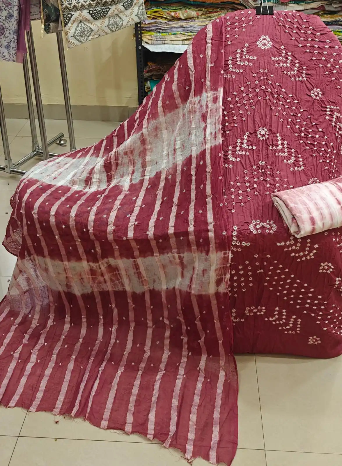 Rich maroon unstitched cotton bandhani dress material with white geometric tie-dye embroidery patterns, paired with a vibrant royal blue contrast dupatta featuring small golden checks.
