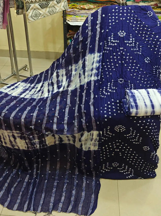 Royal blue cotton bandhani dress material with distinctive circular tie-dye patterns, styled with a deep teal-green contrast dupatta.