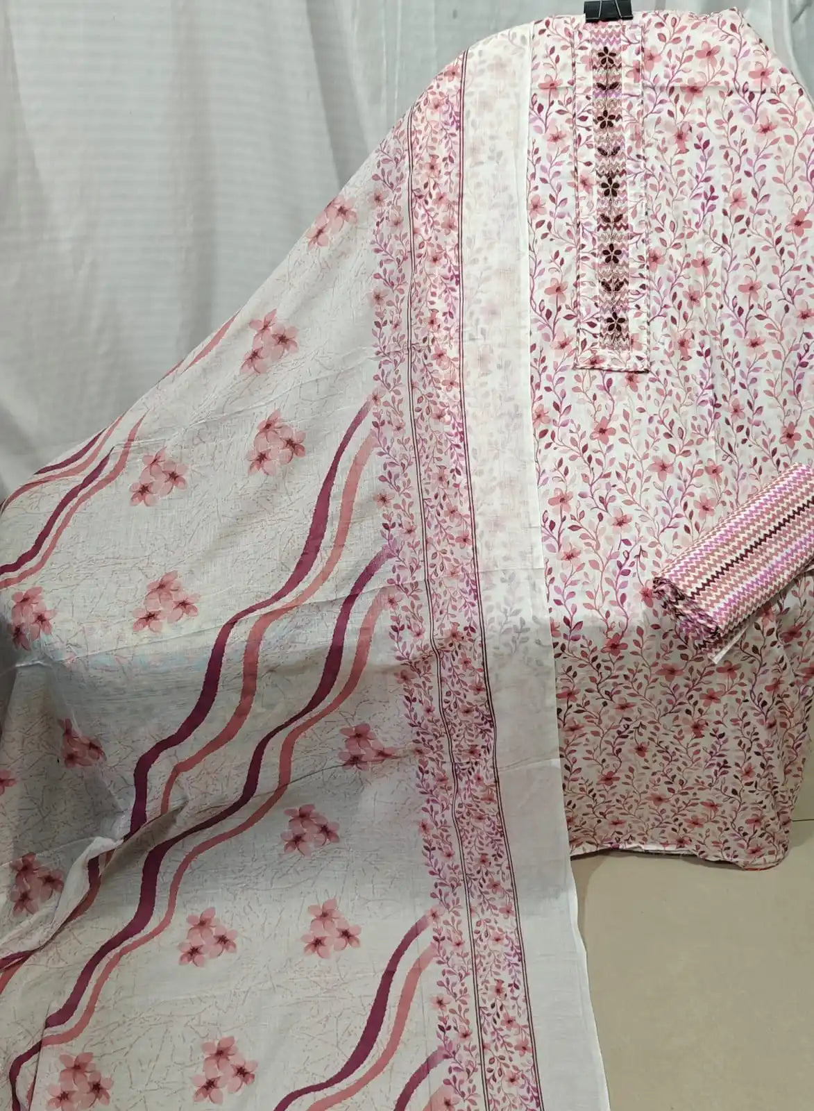A delicate white cotton unstitched dress material by ASC, covered in sweet pink leafy branch prints, featuring a matching vertical embroidered neck panel, and a coordinated white dupatta with wavy pink accents and floral borders.