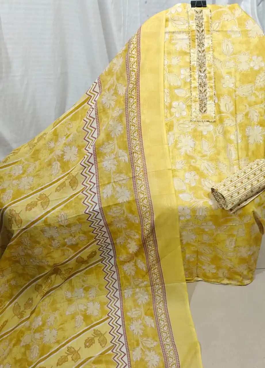 A bright display of a mustard yellow cotton unstitched suit fabric by ASC, decorated with tone-on-tone floral silhouettes, a neat embroidered neck panel, and a coordinated yellow dupatta with dynamic geometric borders.