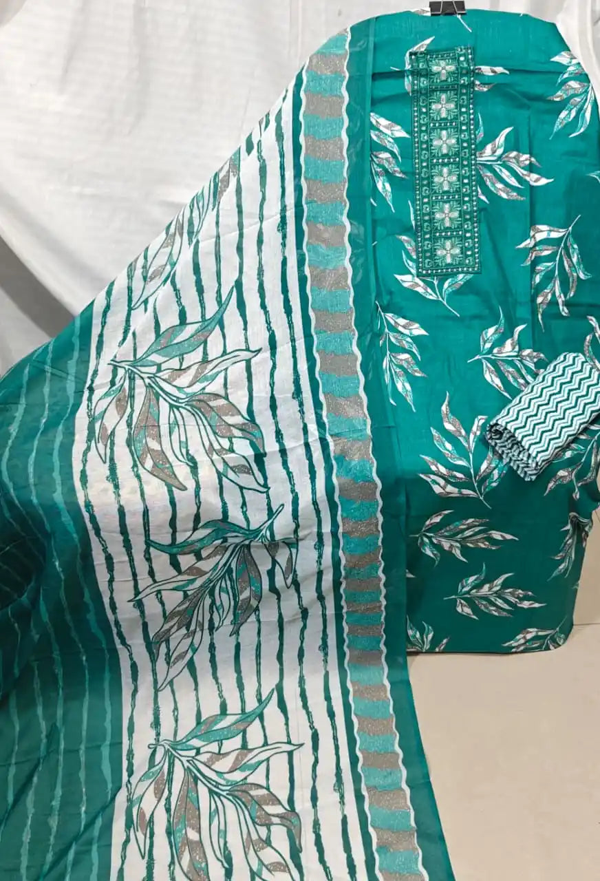 A neat presentation of an emerald green cotton unstitched suit material by ASC, displaying an intricate white leaf branch print, a long embroidered neck patch, a matching zigzag patterned bottom cloth, and a white dupatta detailed with green vertical stripes and leaf patterns.