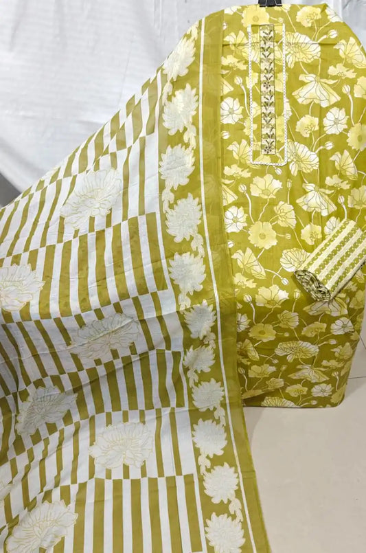 A gorgeous olive mustard yellow cotton unstitched dress material by ASC, showcasing an all-over white lotus pond print, a delicate embroidered lace neck strip, a matching small grid pattern bottom, and a coordinated white dupatta displaying broad mustard block stripes and large floral end-panels.