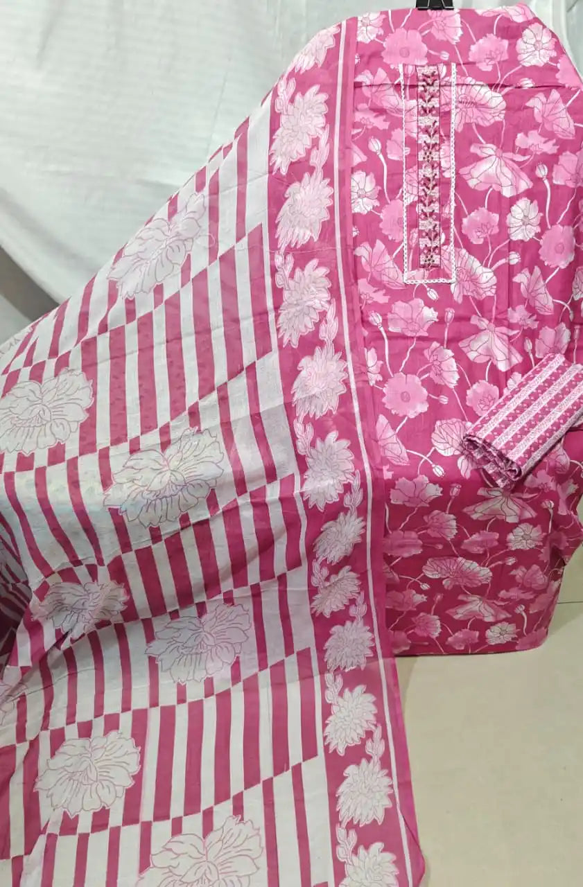 A vibrant candy pink cotton unstitched dress material by ASC, featuring a dense white lotus flower and lily pad print on the shirt, a sleek vertical embroidered neck patch with white lace trim, a small geometric lattice print bottom, and a striking white dupatta adorned with thick pink block stripes and large floral borders.