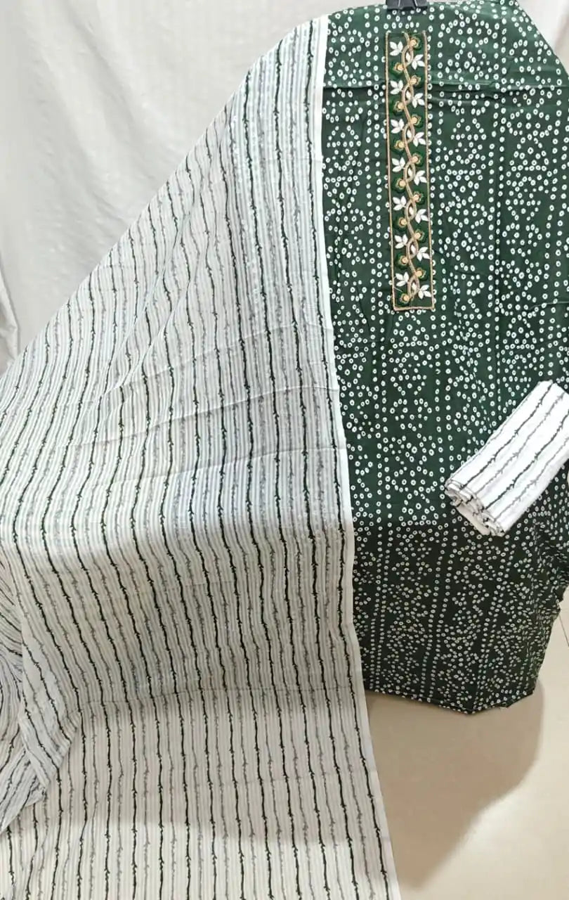 An attractive dark bottle green cotton unstitched suit fabric by ASC, featuring a dense white bandhani dot print, an elegant embroidered neck strip with vine work, a white bottom cloth with green wavy lines, and a light dupatta displaying matching green vertical wavy stripes.