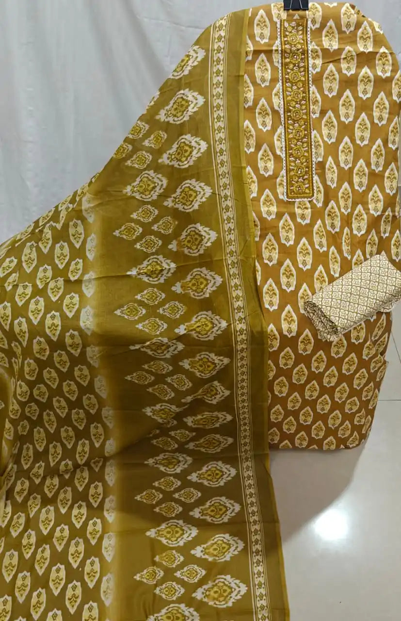 A top view of a mustard yellow cotton unstitched dress material by ASC, showcasing white leaf patterns, an elegant embroidered neck panel, and a coordinated traditional dupatta.