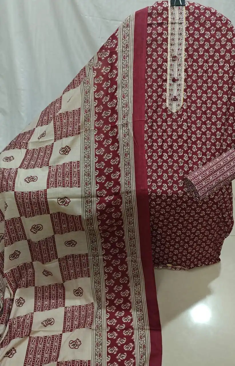 A presentation of a deep maroon cotton unstitched dress material by ASC, featuring tiny white booti prints, an embroidered neck patti, and a cream dupatta with maroon checkerboard patterns.