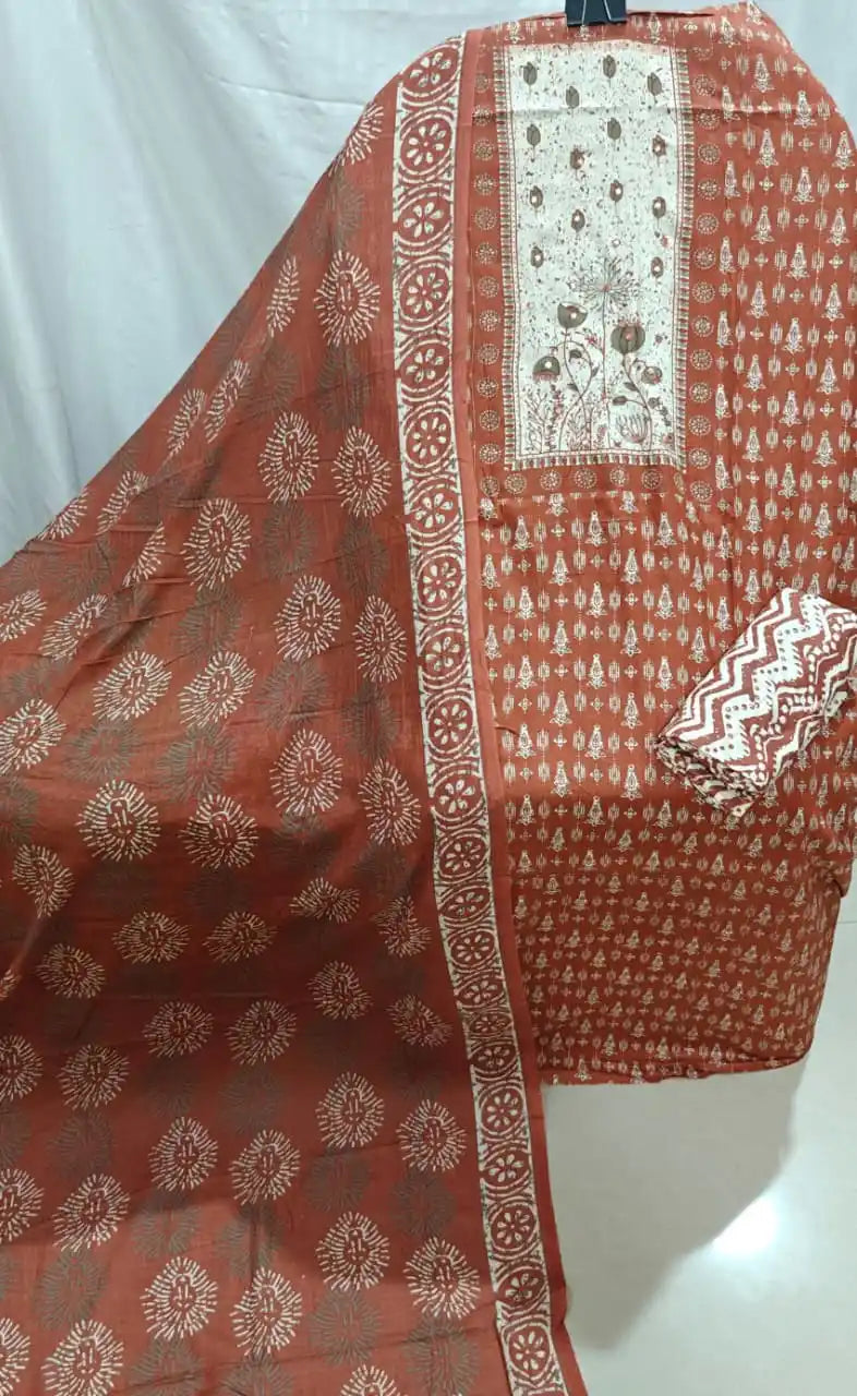 A detailed view of a rust orange cotton unstitched suit material by ASC, showcasing a beautifully embroidered cream neck panel with flowers, fine block prints, and a matching dupatta.