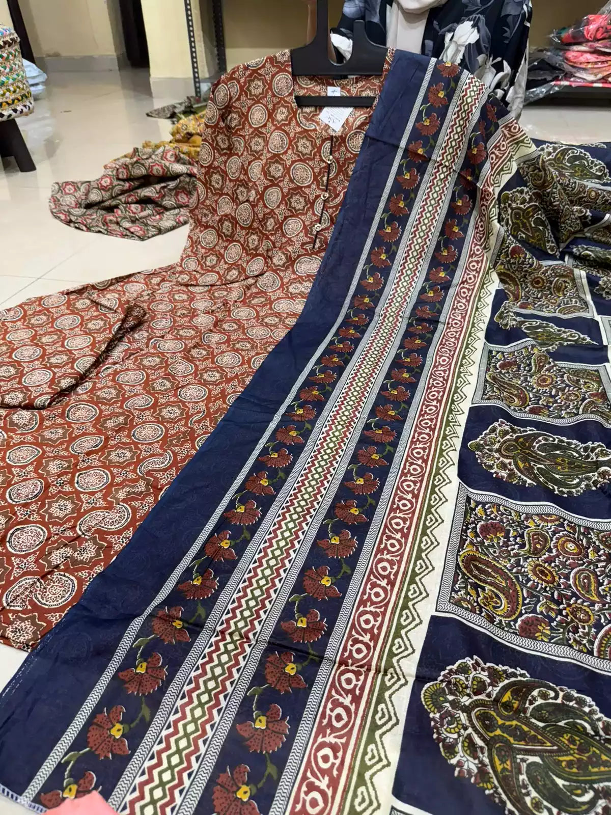 Rust brown cotton Anarkali suit with geometric block prints paired with a navy blue floral printed cotton dupatta.