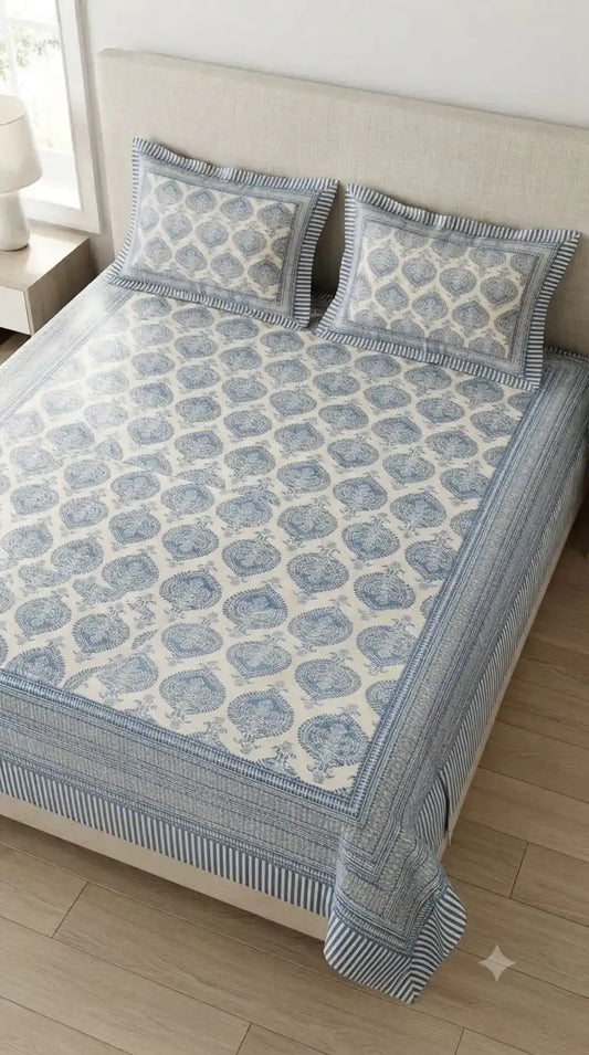 Jaipuri cotton bedsheet set displayed on a bed, featuring intricate blue block print design and matching pillowcases.