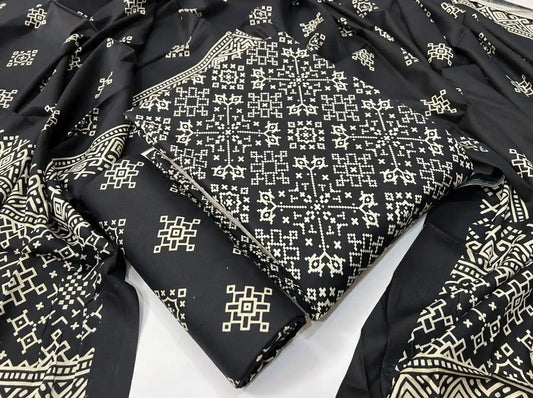 A timeless black rayon unstitched dress material by ASC, decorated with a detailed cream Kutchi cross-stitch print, a matching bottom fold, and a draped dupatta featuring intricate geometric borders.