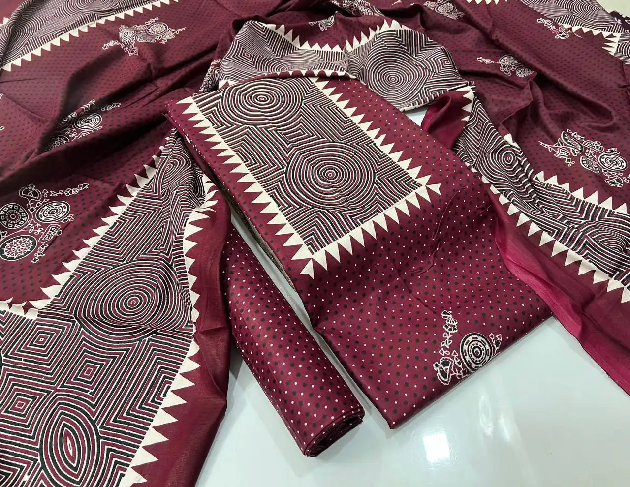 A deep maroon rayon unstitched dress material by ASC, showcasing a micro polka dot pattern on the kurta, a highlighted concentric circle geometric neck panel with saw-tooth edging, and a matching full-length dupatta.