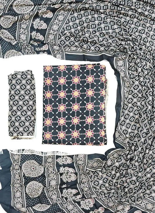 A classic jet black rayon unstitched suit material by ASC, featuring a geometric floral star print on the kurta, a Kutchi cross-stitch printed bottom fold, and a rich multi-patterned dupatta with traditional Ajrakh circular motifs and lattice borders.
