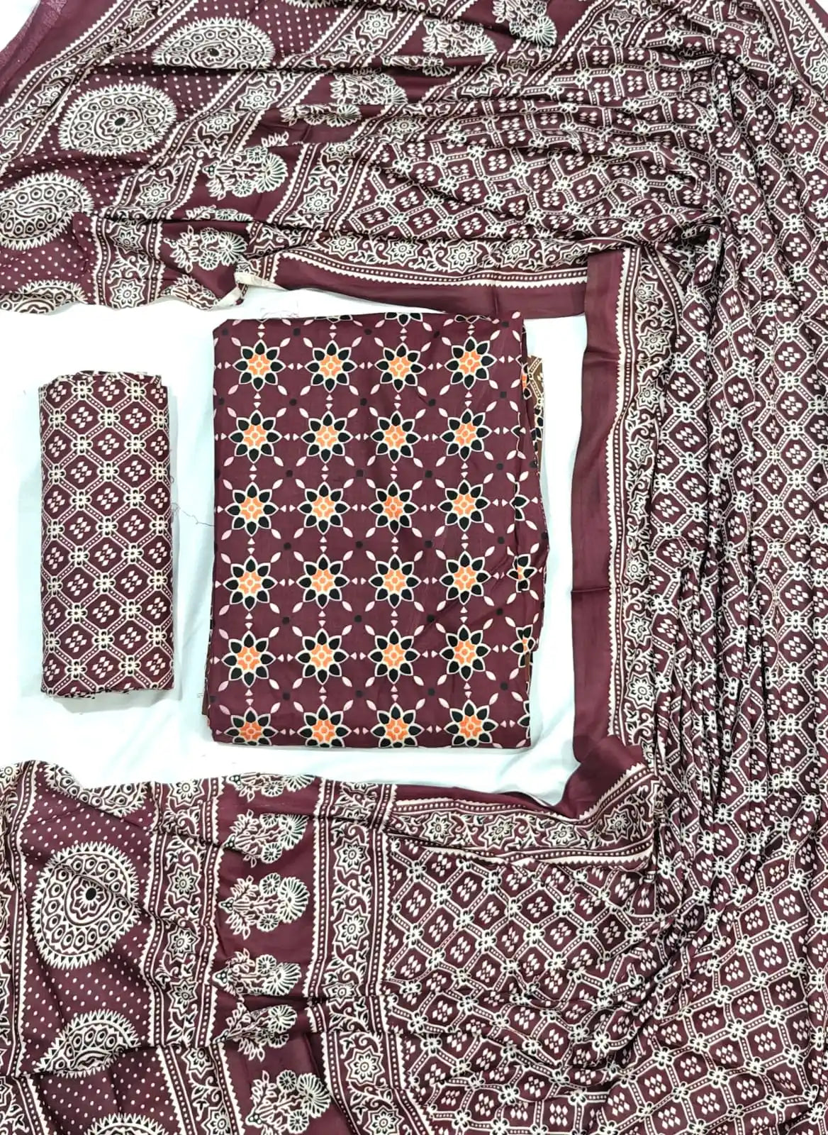 A deep burgundy maroon rayon unstitched dress material by ASC, showcasing a star floral motif across the shirt, a matching Kutchi grid printed bottom, and a full-length draped dupatta with rich Ajrakh inspired patterns.