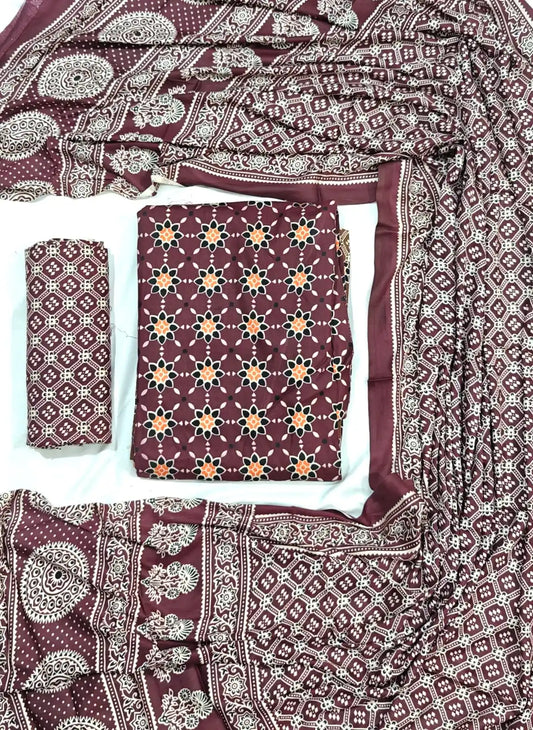 A deep burgundy maroon rayon unstitched dress material by ASC, showcasing a star floral motif across the shirt, a matching Kutchi grid printed bottom, and a full-length draped dupatta with rich Ajrakh inspired patterns.