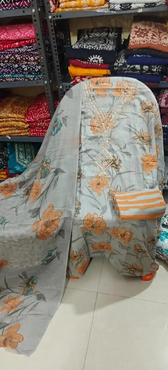 Grey cotton fabric showcasing vibrant orange floral designs, a heavy embroidered neck, and striped pants material.