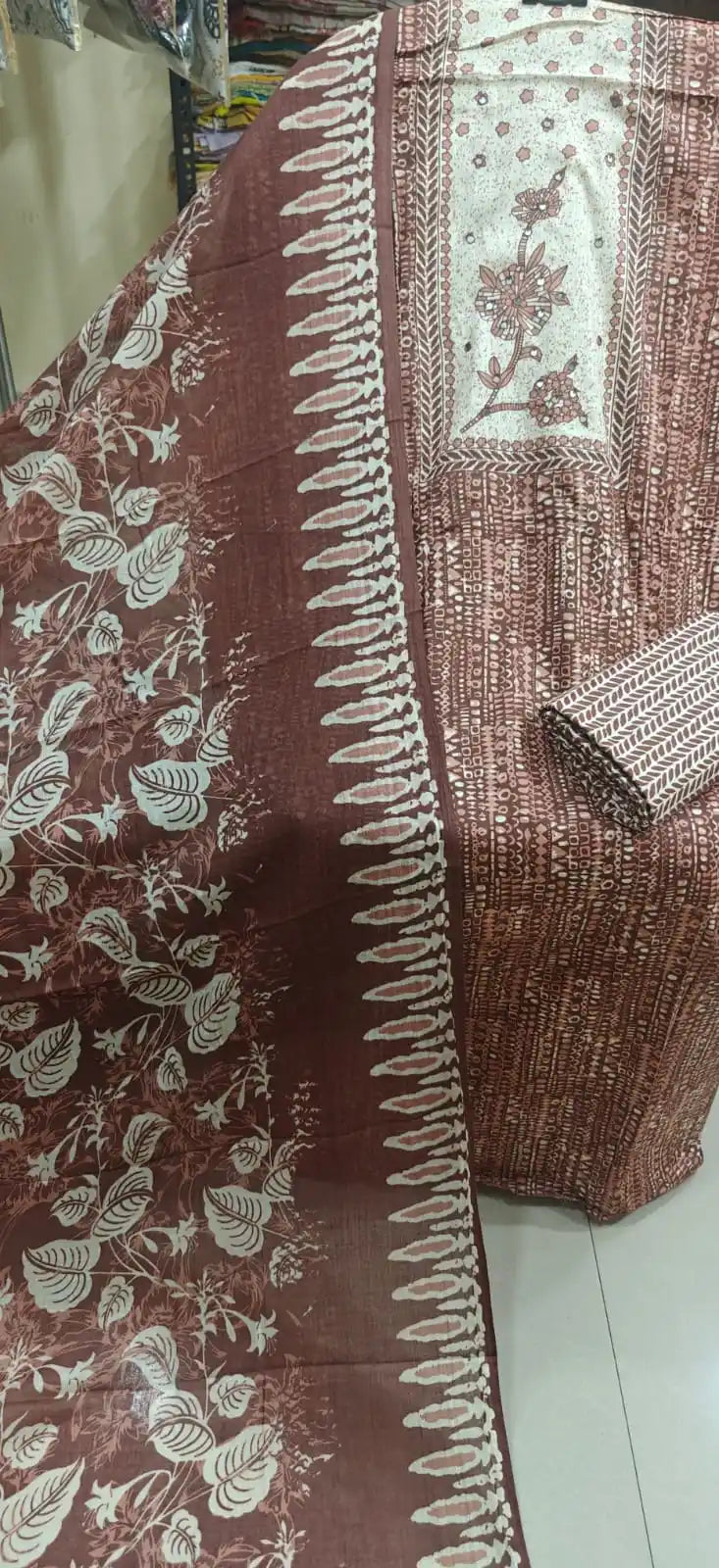 brown cotton suit featuring a highly detailed cream neck panel with embroidered flowers, paired with abstract geometric prints and a leafy vine dupatta.
