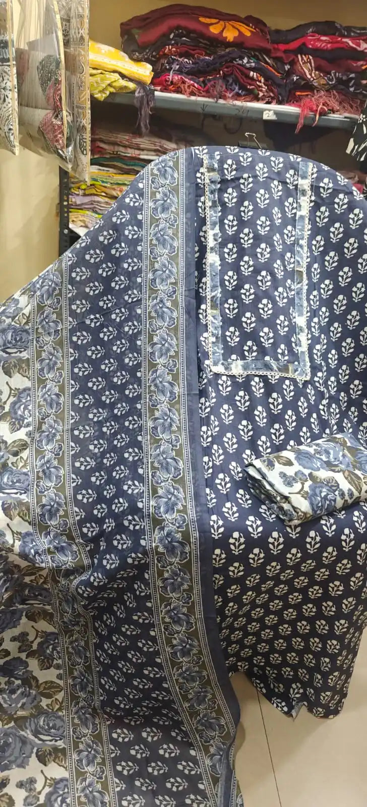 Navy blue cotton suit featuring a lace-bordered embroidered neck panel, delicate white floral bootis, and a matching floral print dupatta.