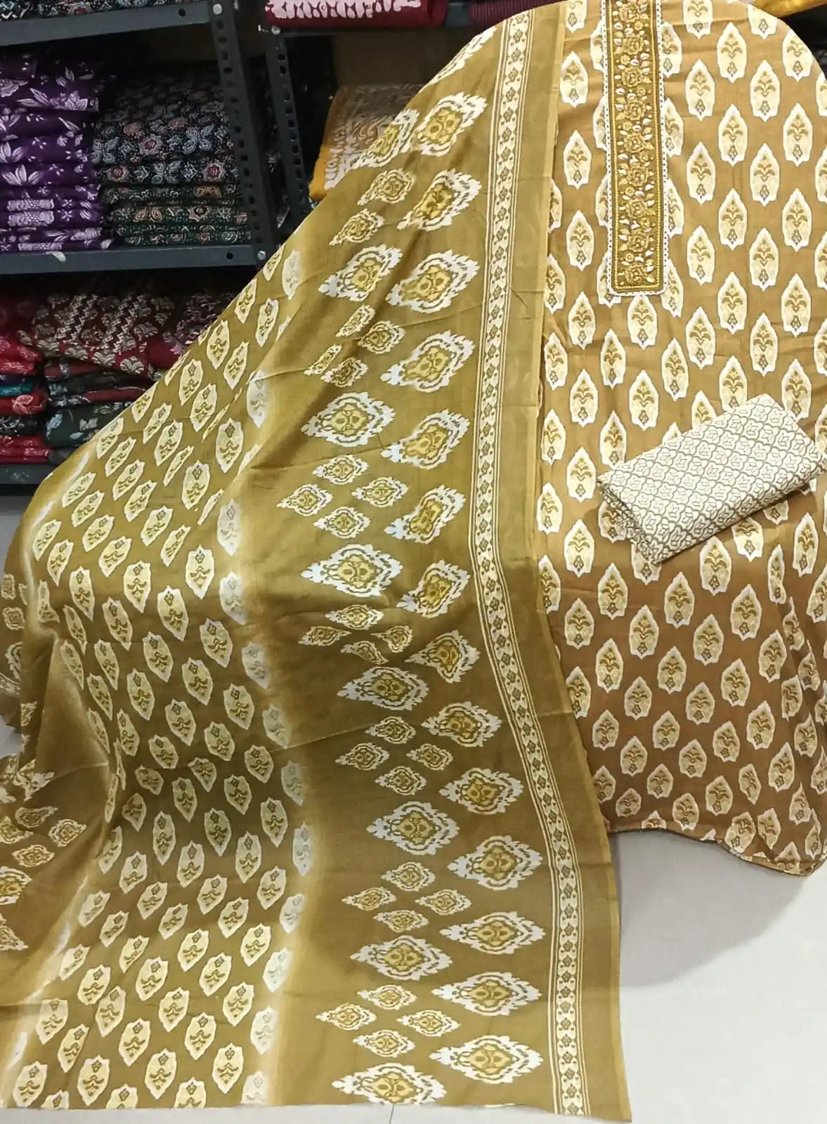 Mustard yellow cotton suit showcasing a detailed floral embroidered neck strip, traditional ikat patterns, and a matching ikat print dupatta.