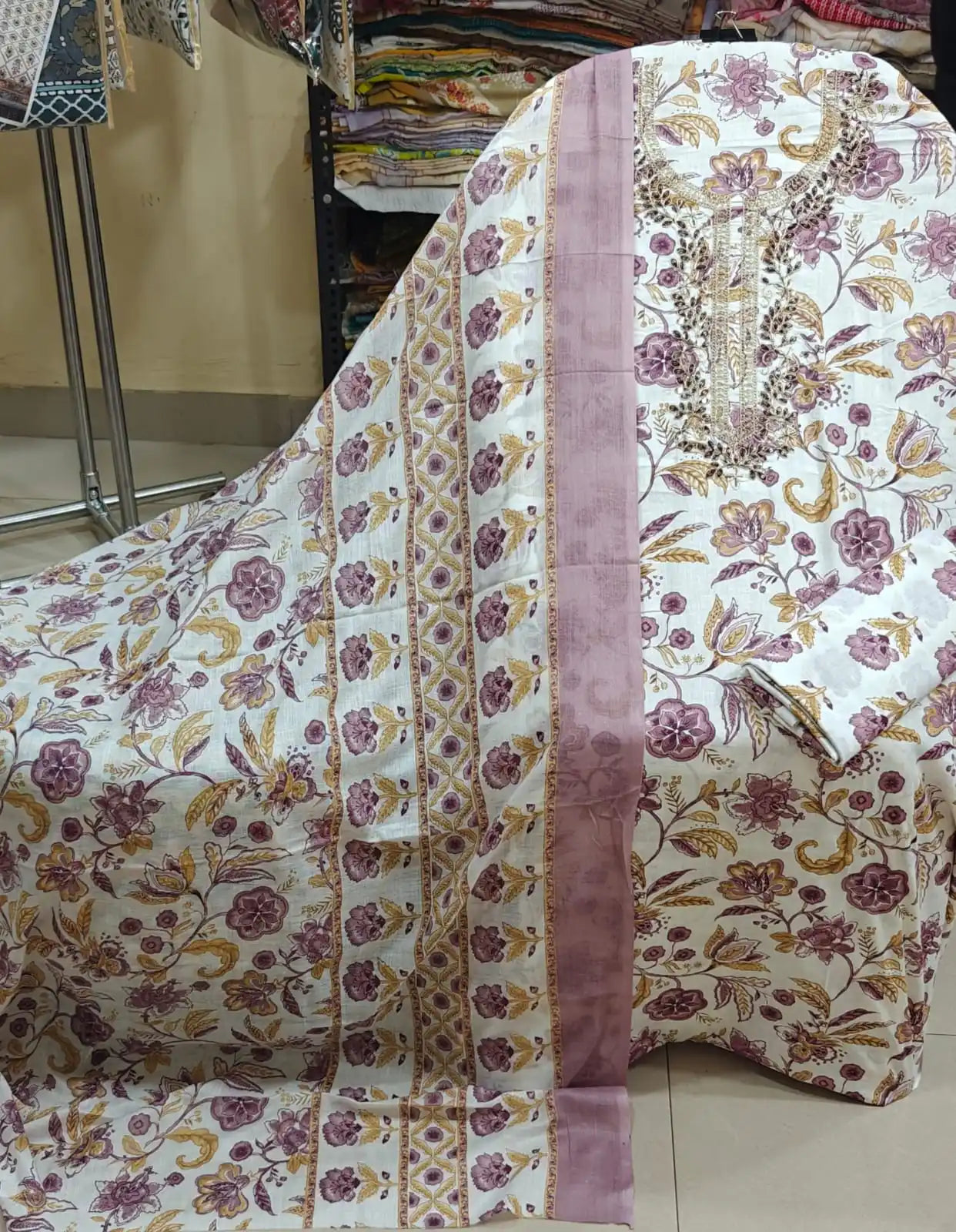 Elegant white cotton fabric featuring purple and golden-brown floral vines with heavy neck embroidery.