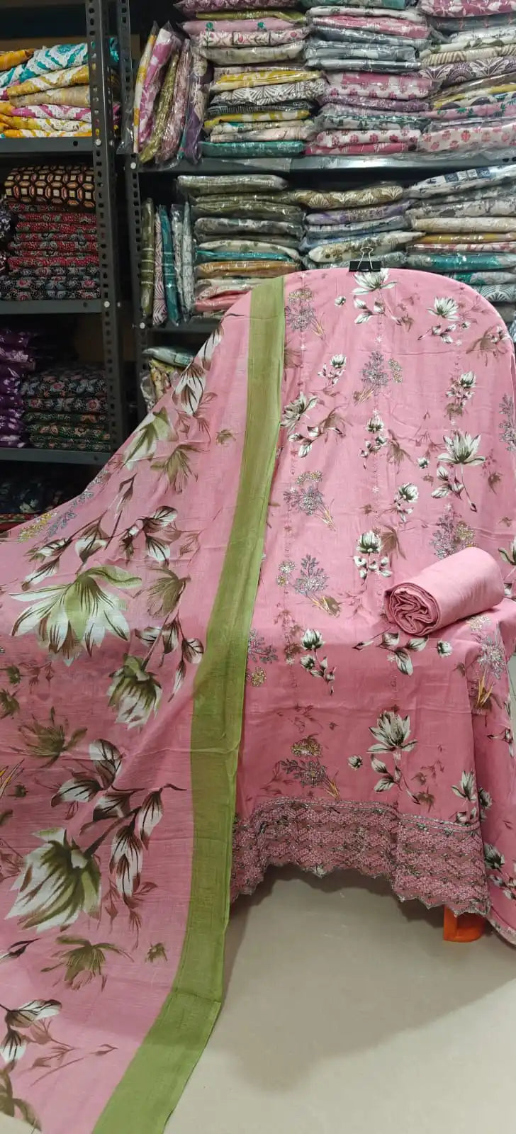Soft blush pink unstitched cotton suit featuring a delicate white and green lotus floral print, paired with a matching pink bottom fabric and a coordinated dupatta with a green border highlight.