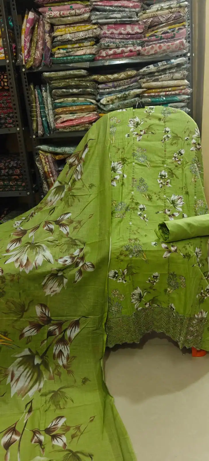 Bright lime green unstitched cotton salwar suit showcasing large white and brown floral motifs, styled with a matching green folded bottom fabric and a lightweight printed dupatta.