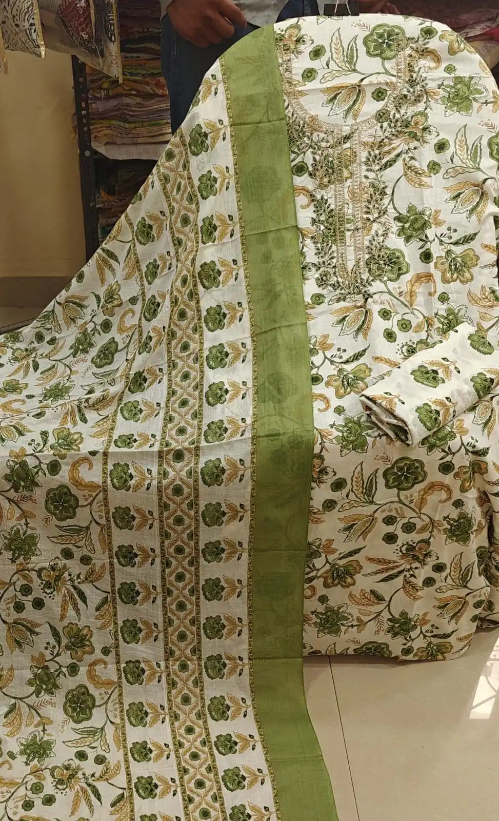 White base cotton suit piece decorated with leafy green floral vines and detailed neck work.