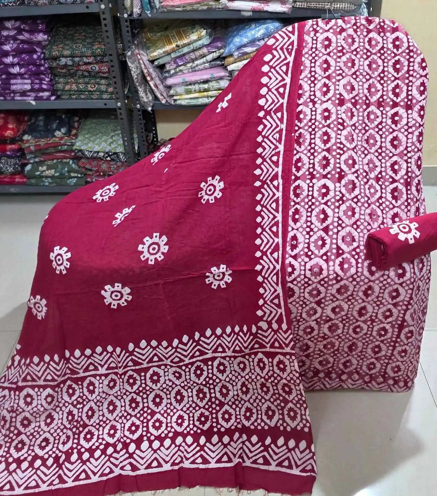Unstitched maroon cotton suit fabric featuring an all-over white geometric batik print on the kameez, paired with a matching solid maroon bottom fabric roll, and a coordinated maroon dupatta adorned with white wheel-like motifs and broad batik borders.